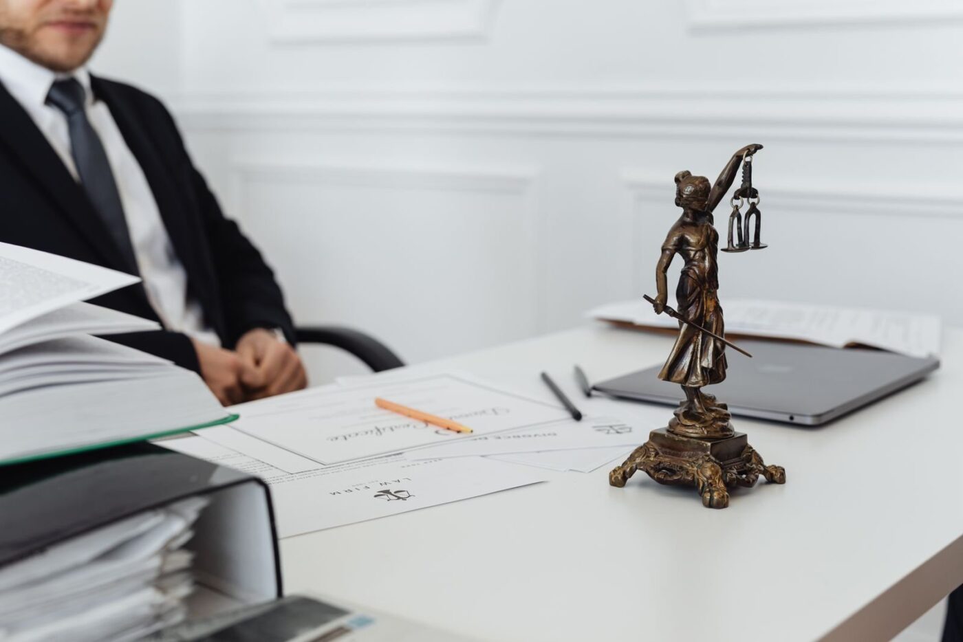 Justitia-Figur auf einem Schreibtisch mit Unterlagen in einer Rechtsanwaltskanzlei