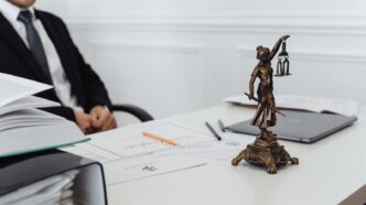 Justitia-Figur auf einem Schreibtisch mit Unterlagen in einer Rechtsanwaltskanzlei