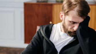 Nachdenklicher Mann sitzt mit gesenktem Blick auf einem Stuhl