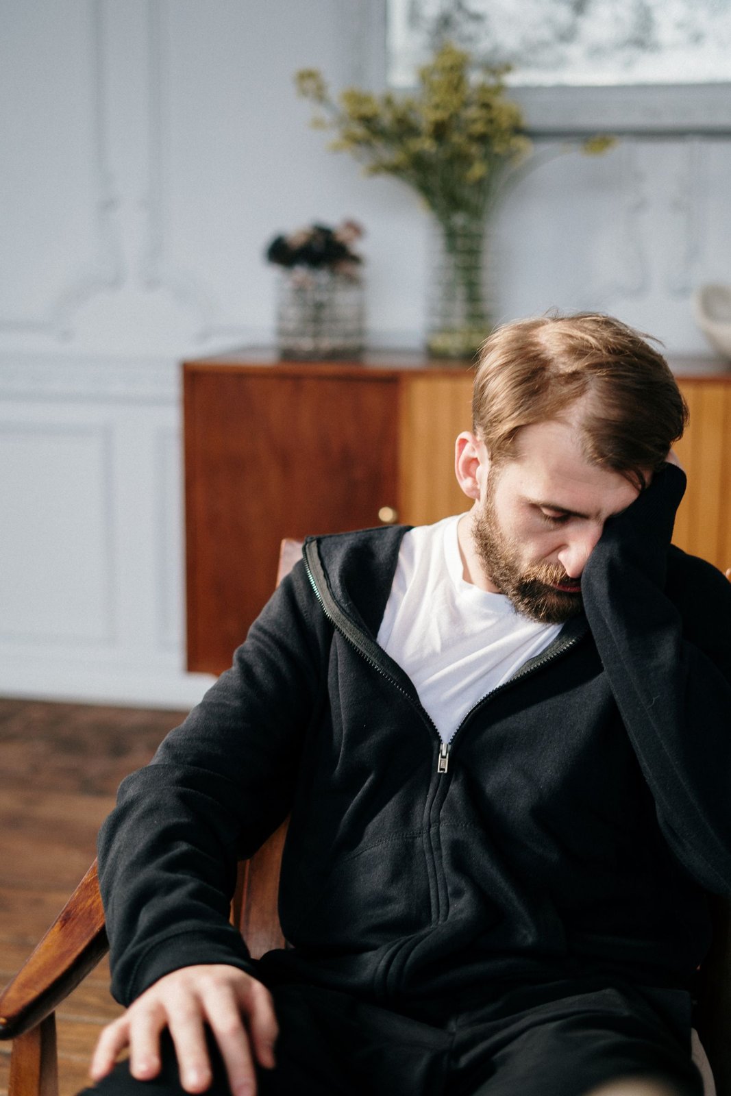 Nachdenklicher Mann sitzt mit gesenktem Blick auf einem Stuhl