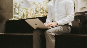 Mann im Hemd arbeitet mit dem Laptop auf dem Schoss in einer Buerolobby