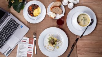 Gedeckter Restauranttisch mit Suppe, Salat und Laptop von oben fotografiert