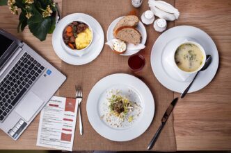 Gedeckter Restauranttisch mit Suppe, Salat und Laptop von oben fotografiert