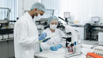 Zwei Wissenschaftler, die in einer modernen Laborumgebung an einer Forschung zusammenarbeiten und fortschrittliche Geräte verwenden.