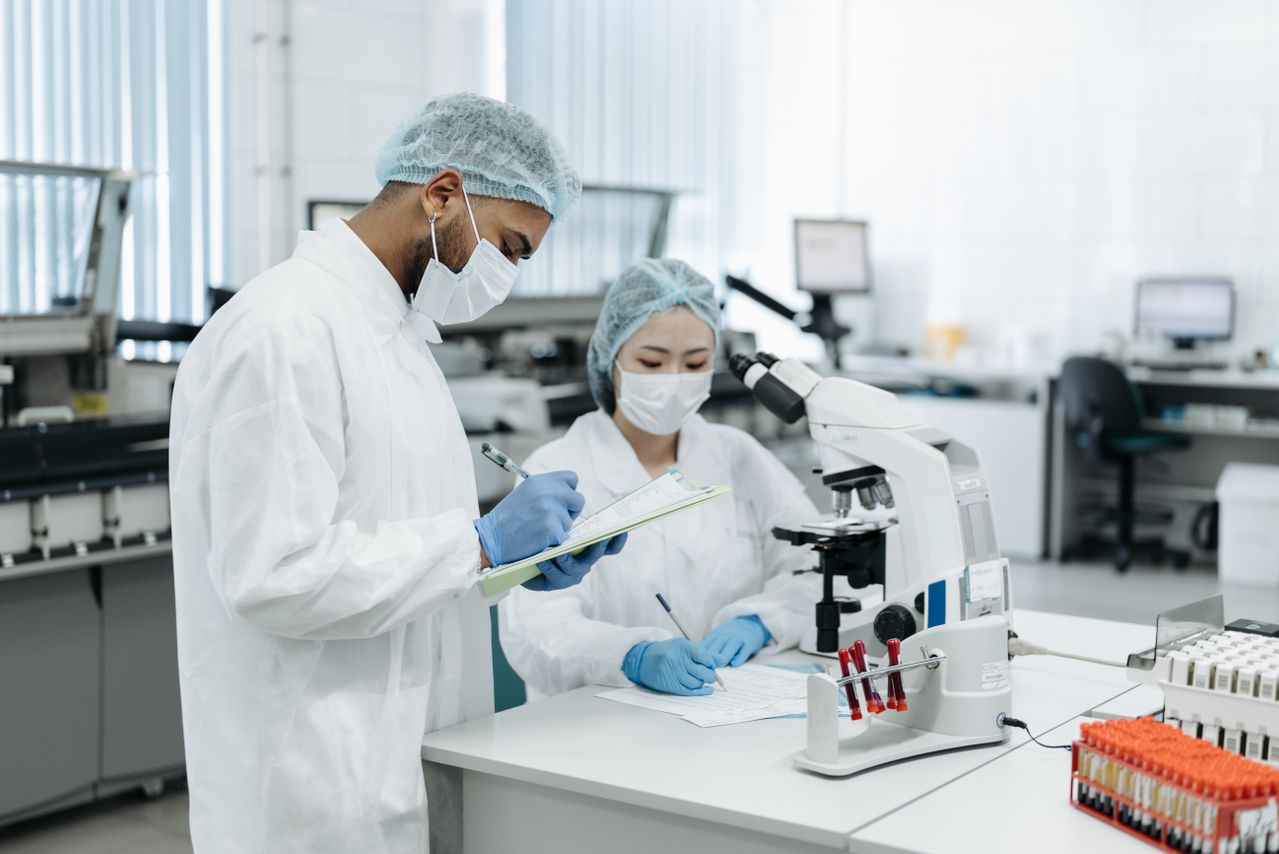 Zwei Wissenschaftler, die in einer modernen Laborumgebung an einer Forschung zusammenarbeiten und fortschrittliche Geräte verwenden.